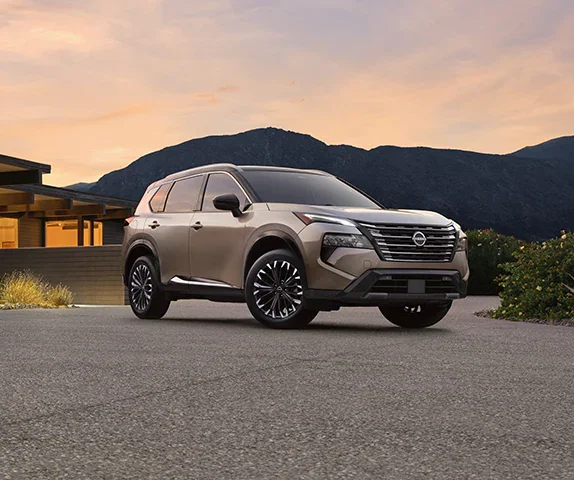 A grey Rogue SUV parked front of building